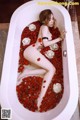 A woman laying in a bathtub filled with rose petals.