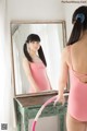 A woman in a pink leotard standing in front of a mirror.