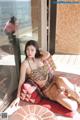 A woman in a leopard print bikini sitting on a red couch.