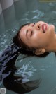 A woman floating in a pool of water with her eyes closed.