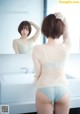 A woman standing in front of a mirror in a bathroom.