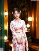 A woman in a white kimono standing in front of a door.