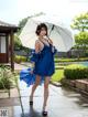 A woman in a blue dress holding an umbrella.